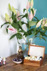 Essential oils on a table with mixing bowl, Buddha and LIlies in a vase